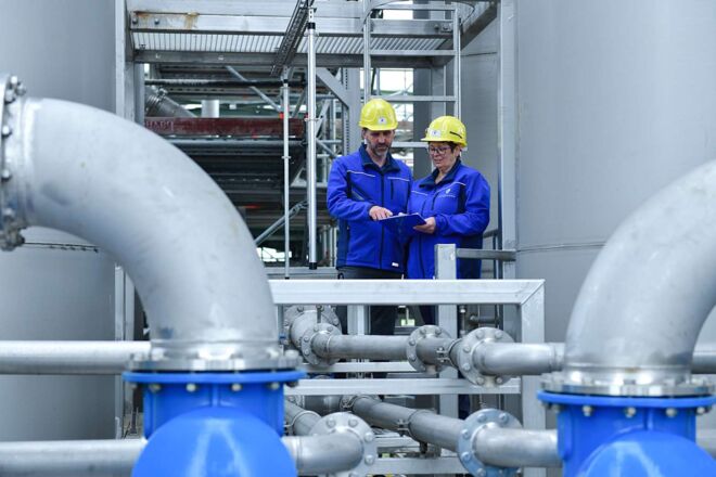 Auf diesem Bild sehen Sie zwei Personen, welche die aktuellen Werte der Abwasseranlage prüfen.