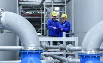 Auf diesem Bild sehen Sie zwei Personen, welche die aktuellen Werte der Abwasseranlage prüfen.